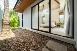 Un dormitorio en una villa con vistas a un árbol. en Anchan Villas Phuket - 4 BR Signature Pool Villa by Escape Villas, en Ban Phru Champa
