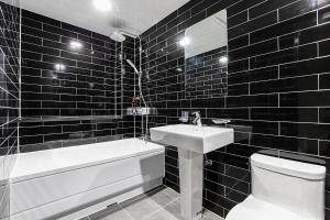 um banheiro de azulejos pretos com um vaso sanitário e uma pia em HOTEL Juno em Yongin