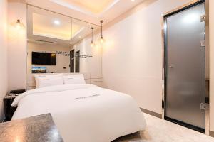 um quarto com uma cama branca e uma tv em HOTEL Juno em Yongin mais 8 fotografias