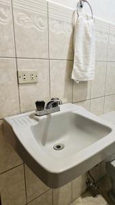lavabo blanco en el baño con toalla en Hostal casa el calvarito, en León