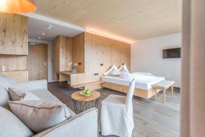 a bedroom with a bed and a desk at Kronplatz-Resort Hotel Kristall in Valdaora