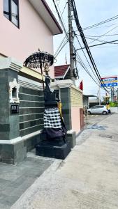 a statue sitting on the side of a building with an umbrella at BEE ROOM Sanur in Sanur