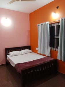 a bedroom with a bed with orange walls and a window at Lakshmi Nilaya Family Homestay on Hilltop-360 Degree View in Madikeri