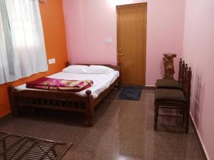 a small bedroom with a bed and a chair at Lakshmi Nilaya Family Homestay on Hilltop-360 Degree View in Madikeri