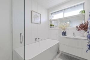 a white bathroom with a tub and a sink at Chic Coastal Retreat in Ocean Grove