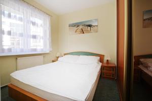 1 dormitorio con cama blanca y ventana en Apartament Morski en Kołobrzeg