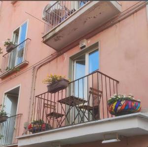 a pink building with chairs on a balcony at Casa AL CORSO Pozzuoli Centro in Pozzuoli +4 photos