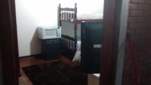 Cette chambre comprend un lit et une télévision. dans l'établissement Suite Campos do Jordão, à Campos do Jordão