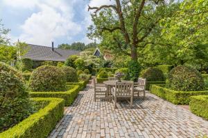 een patio met een tafel en stoelen in een tuin bij Bij Janneke in Sleeuwijk