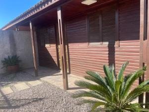 Una casa con una puerta de madera y una planta delante de ella. en Las Palmeras, en Chuí