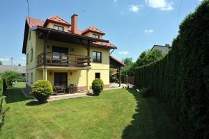a yellow house with a fence in the yard at Dom U Kuby in Hoczew