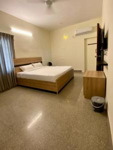 Un dormitorio con una cama y un televisor. en Reliable Nest, en Chennai