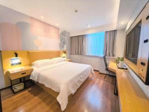 a bedroom with a large white bed and a desk at GreenTree Inn Ganzhou Gan County Bus Station in Meilin