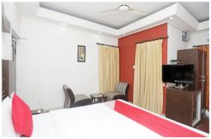 a room with a bed and chairs and a tv at Hotel Santosh Classic Residency হোটেল সন্তোষ ক্লাসিক রেসিডেন্সি Puri - Lift, Parking, Swimming Pool & Spacious AC Rooms in Puri