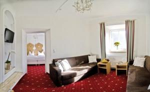 a living room with a couch and a red carpet at Hotel Ansitz Haidenhof in Lienz