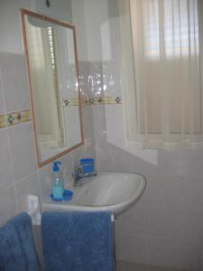 a bathroom sink with a mirror and a blue towel at Le Mimose in Cala Liberotto