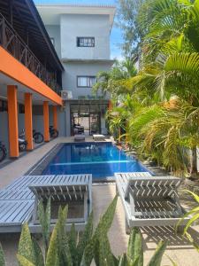 a resort pool with two benches and palm trees at Tropica Gili Hotel - Free Access Gym and Coworking Space in Gili Trawangan