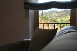 a bed with a pillow in front of a window at La Caseta del Priorat III in Porrera +12 photos