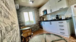 a kitchen with white cabinets and a table and chairs at Green Cape Guest House in Makhinjauri