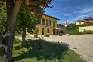 a yellow house with a tree next to a gravel road at The Green Guest House in Barolo