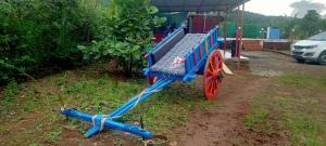 a blue cart with red wheels parked in a field at Shravani Farms in Tala