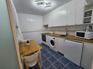 Una cocina con gabinetes blancos y una mesa y un microondas. en Central Park, en Bermeo