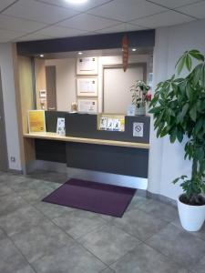 a reception desk in an office with a potted plant at B&B HOTEL Clermont-Ferrand Nord Riom in Riom