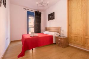 um quarto com uma cama com um cobertor vermelho em Apartamento Castillejos em Tarifa