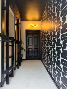 a hallway with a black door and a wall at Bishop Hostel in Dallas