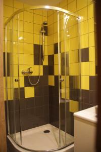 ワルシャワにあるAkademik Praskiの黄色と黒のタイル張りのバスルーム(シャワー付)