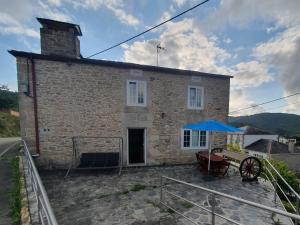 a stone house with a blue umbrella in front of it at Casa en zona rural in Cervo