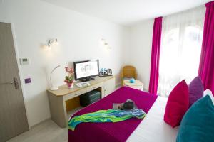 a bedroom with a bed with pink sheets and a desk at Cristal Hôtel & Spa in Cannes