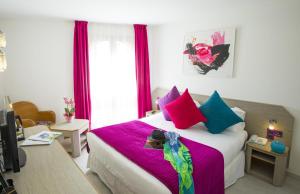 a bedroom with a large bed with colorful pillows at Cristal Hôtel & Spa in Cannes