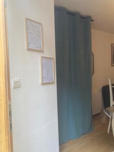 une pièce avec un rideau bleu et des certificats sur un mur dans l'établissement appartement T2 RDC, à Ax-les-Thermes 5 autres photos