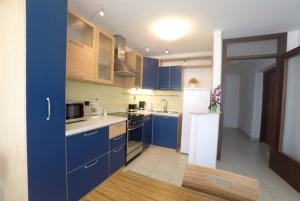 a kitchen with blue cabinets and a white refrigerator at Apartment Pizzybondo in Split