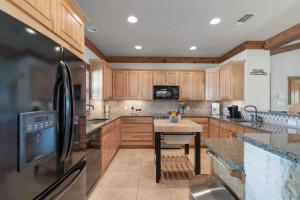 a kitchen with wooden cabinets and a black refrigerator at Ranch Retreat Creek View - Pool Table and Fire Pit in Morris Ranch