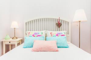 ein Schlafzimmer mit einem weißen Bett mit blauen und rosa Kissen in der Unterkunft Calado Apartments in Lissabon