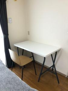 a white table and a chair next to a bed at Apartment in Narita 120 in Narita