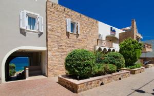 a brick building with a courtyard with bushes in front of it at Plaka Studios in Karfas