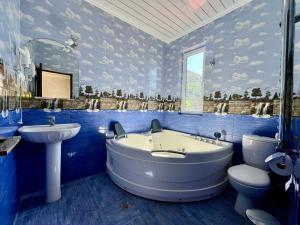 a blue bathroom with a tub and a sink and a toilet at Kirch Hotel & Restaurant in Goris