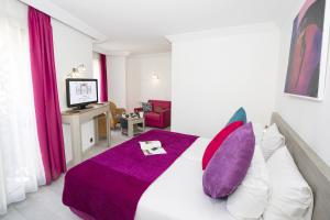 a bedroom with a large bed with purple pillows at Cristal Hôtel & Spa in Cannes