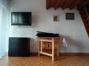 ein Fernseher an der Wand mit einem Tisch und ein Schreibtisch mit einem Tisch in der Unterkunft charmant studio Mezzanine vue mer,près du port in La Londe-les-Maures
