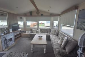 a living room with a couch and a coffee table at 3-Bed Caravan Sleeps 8 Pool & Beach in Chapel Saint Leonards