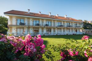 a large building with pink flowers in front of it at Apartamentos La Bolera in Isla