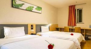 une chambre d'hôtel avec deux lits avec des draps blancs et une rose rouge dessus dans l'établissement 7 Days Inn Urumqi Guangming Road Beimen Metro Station, à Ürümqi