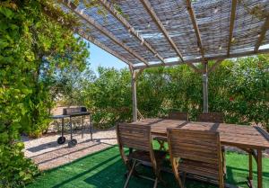a wooden table and chairs under a wooden pergola at Mallorquin Oasis with natural pool 5min from the beach in Port de Pollensa