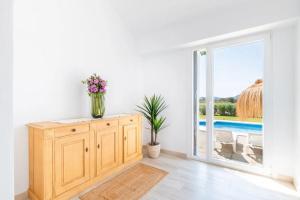 a room with a wooden cabinet with a vase of flowers on it at Mallorquin Oasis with natural pool 5min from the beach in Port de Pollensa +21 photos