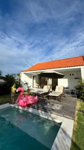 a swimming pool with a pink flamingo in front of a house at Vila Billy II in Munggu +7 photos