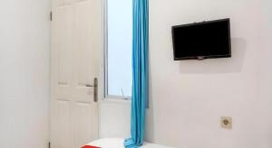 ジャカルタにあるSuper OYO 91074 Stariez Senen Syariahのドア、テレビ、窓が備わる客室です。