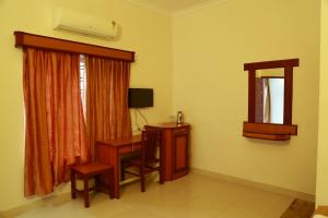 a room with a desk and a mirror and a window at Seethal Residency in Kattappana